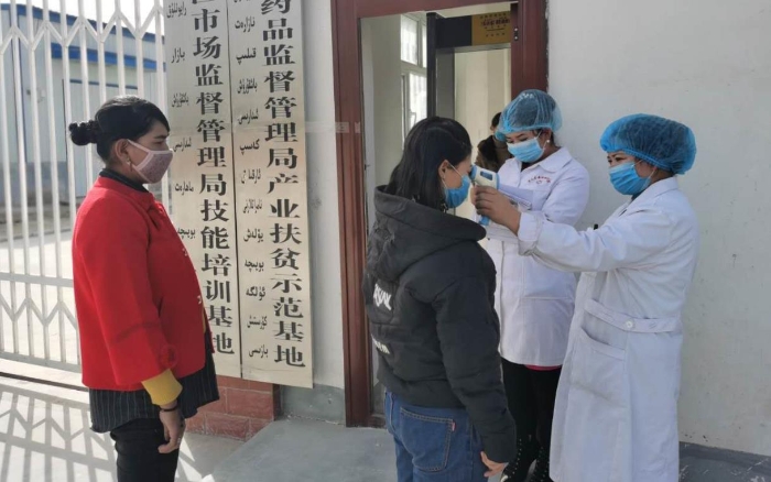 工人在進入工廠前測量體溫并登記。（駐村工作隊供圖）