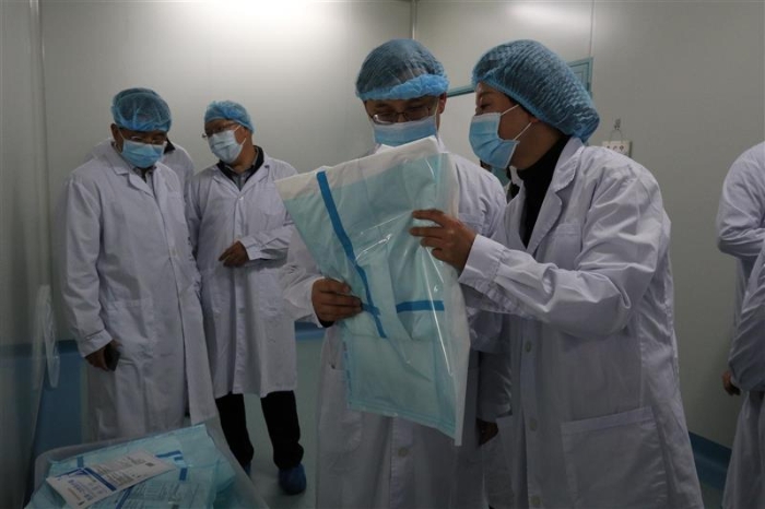 圖為云南省藥監(jiān)局黨組書(shū)記、局長(zhǎng)劉本軍（右二）檢查該企業(yè)生產(chǎn)的醫(yī)用一次性防護(hù)服。（云南省藥監(jiān)局供圖）