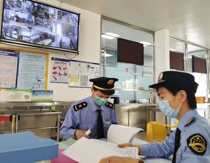 海淀區市場監管局監管人員檢查學校食堂進貨記錄。（中國食品藥品網記者王曉冬 攝）
