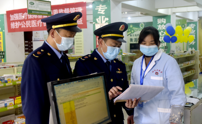 圖為執(zhí)法人員在一家藥店檢查疫情防控藥械銷售記錄。