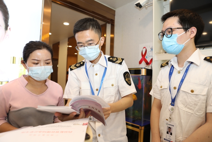 圖為抽檢人員向經(jīng)營(yíng)者宣貫化妝品監(jiān)管法規(guī)文件。