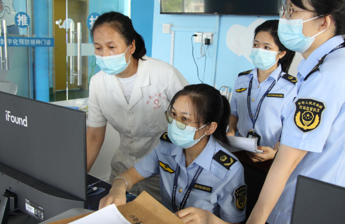 圖為鐘山縣市場監管局執法人員在一家疫苗接種單位檢查相關資質文件。